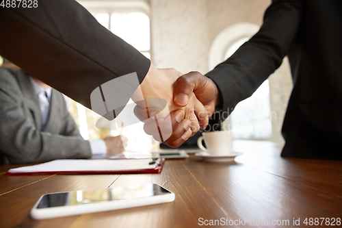 Image of Close up of businessmen shaking hands in conference room