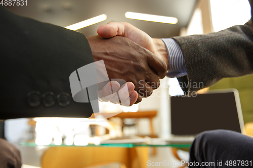 Image of Close up of businessmen shaking hands in conference room