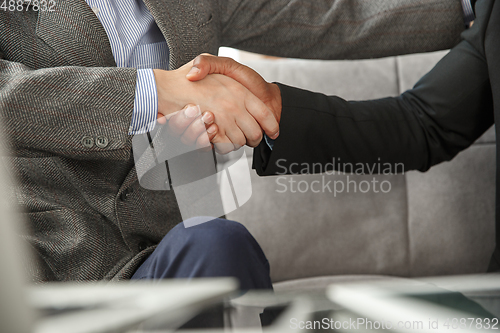 Image of Close up of businessmen shaking hands in conference room