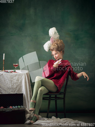 Image of Young woman as Marie Antoinette on dark background. Retro style, comparison of eras concept.