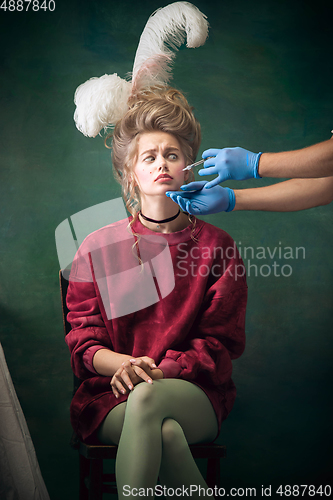 Image of Young woman as Marie Antoinette on dark background. Retro style, comparison of eras concept.