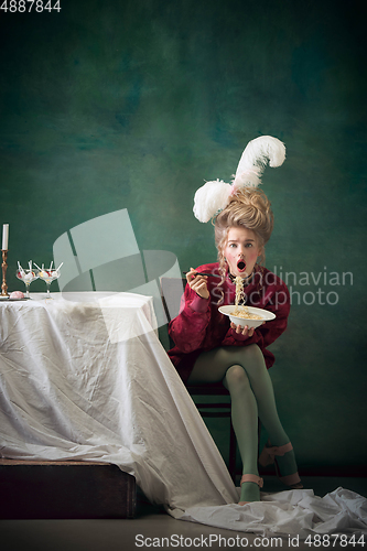 Image of Young woman as Marie Antoinette on dark background. Retro style, comparison of eras concept.