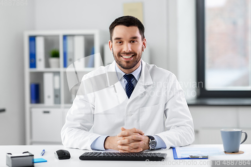 Image of doctor in earphones having video call at clinic