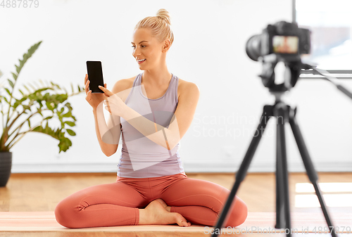 Image of woman with phone streaming for yoga blog at home