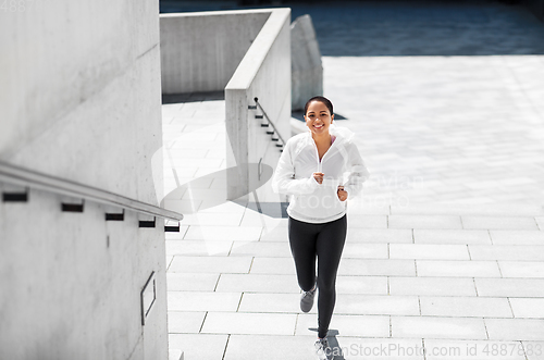 Image of african american woman running upstairs outdoors