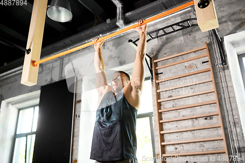 Image of man exercising on bar and doing pull-ups in gym