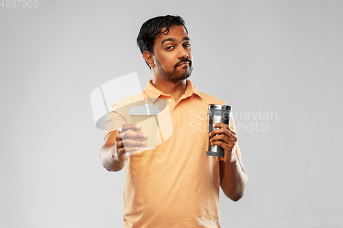 Image of man comparing thermo cup or tumbler and coffee cup