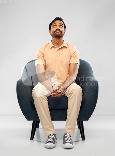 Image of happy smiling young indian man sitting in chair