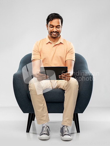 Image of happy indian man with tablet pc computer in chair