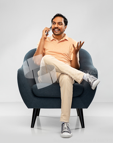 Image of happy indian man calling on smartphone in chair