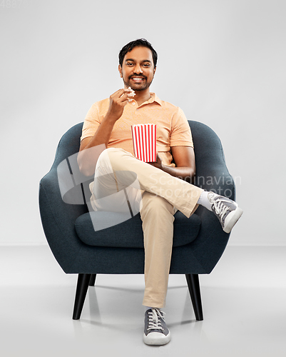 Image of happy smiling indian man eating popcorn in chair