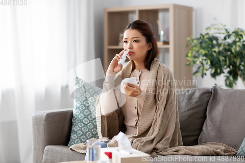Image of sick asian woman with nasal spray medicine at home
