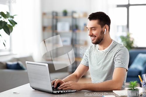 Image of man with laptop and earphones at home office