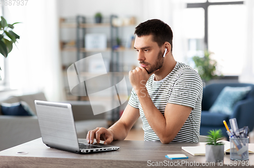 Image of man with laptop and earphones at home office