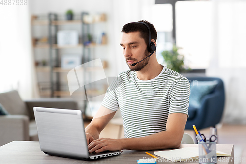 Image of man with headset and laptop working at home