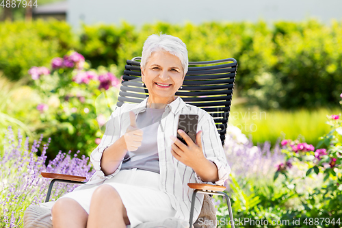 Image of happy senior woman with phone at summer garden