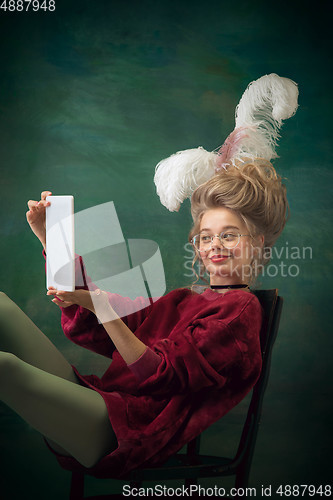 Image of Young woman as Marie Antoinette on dark background. Retro style, comparison of eras concept.