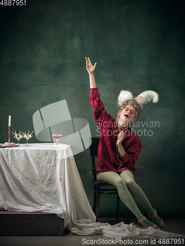 Image of Young woman as Marie Antoinette on dark background. Retro style, comparison of eras concept.