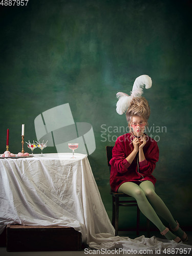 Image of Young woman as Marie Antoinette on dark background. Retro style, comparison of eras concept.