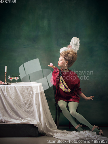 Image of Young woman as Marie Antoinette on dark background. Retro style, comparison of eras concept.