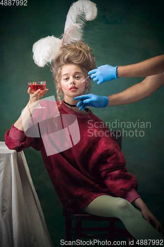 Image of Young woman as Marie Antoinette on dark background. Retro style, comparison of eras concept.