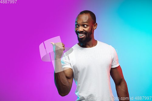 Image of African-american young man\'s portrait on gradient studio background in neon