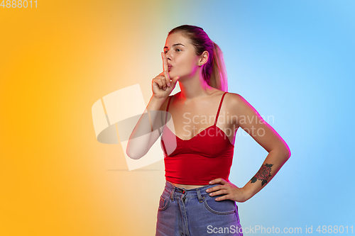 Image of Caucasian young woman\'s portrait on gradient studio background in neon