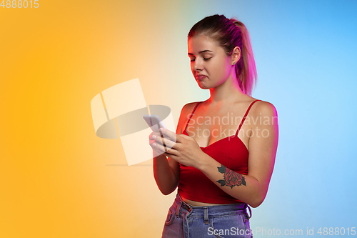 Image of Caucasian young woman\'s portrait on gradient studio background in neon