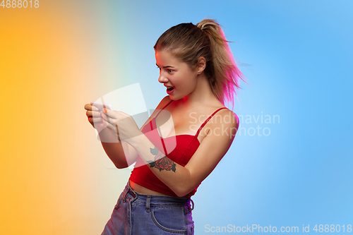 Image of Caucasian young woman\'s portrait on gradient studio background in neon