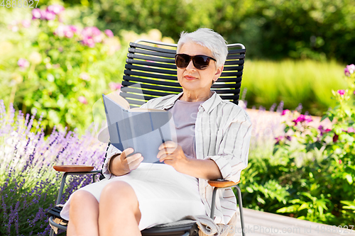 Image of happy senior woman reading book at summer garden