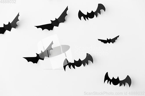 Image of flock of black paper bats over white background
