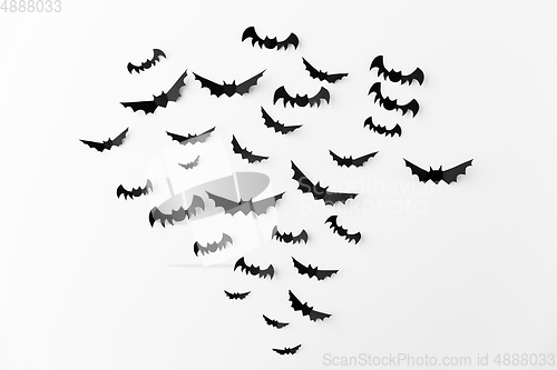 Image of flock of black paper bats over white background