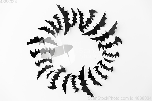 Image of flock of black paper bats over white background