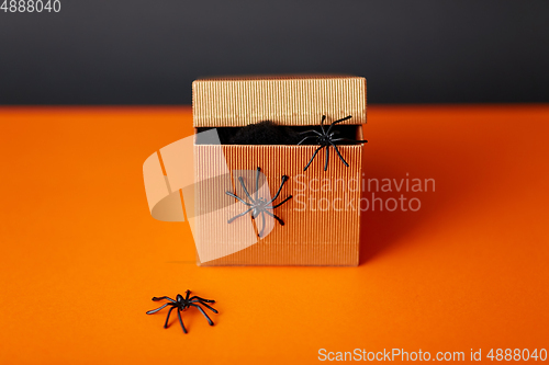 Image of toy spiders crawling out of gift box on halloween