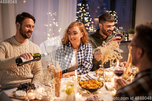 Image of happy friends with red wine at christmas party