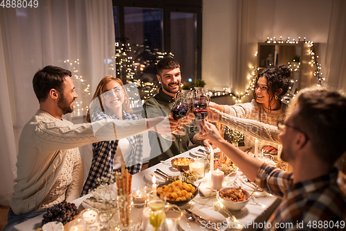 Image of happy friends drinking red wine at christmas party