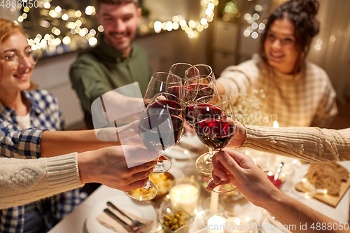 Image of happy friends drinking red wine at christmas party