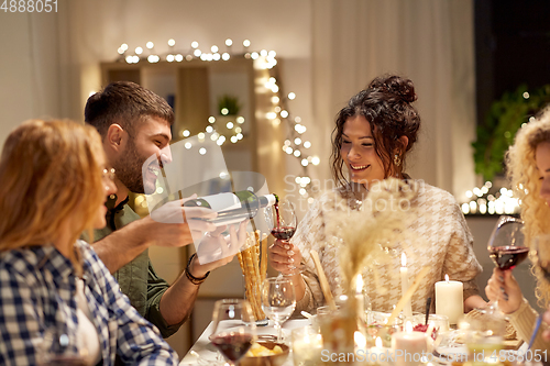 Image of happy friends with red wine at christmas party