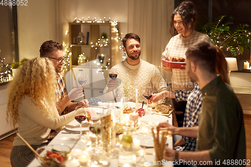 Image of happy friends having christmas dinner at home