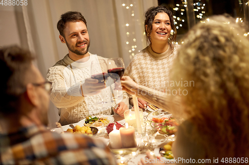 Image of happy friends drinking red wine at christmas party