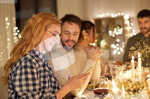 Image of friends with cellphone having dinner party at home