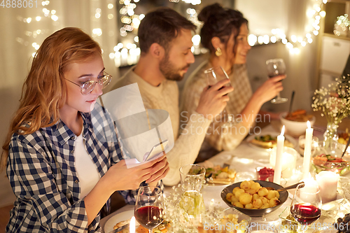 Image of woman with smartphone at dinner party with friends