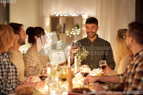 Image of happy friends drinking red wine at christmas party