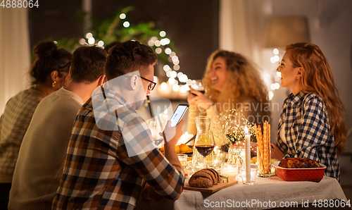 Image of man with smartphone at dinner party with friends