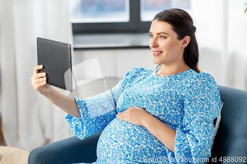 Image of happy pregnant woman with tablet pc at home