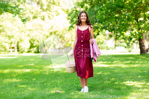 Image of happy woman with picnic basket and blanket at park