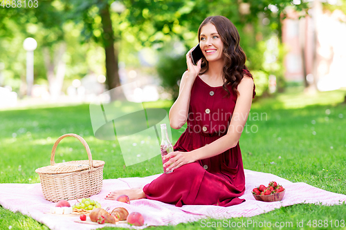 Image of woman calling on smartphone on picnic at park