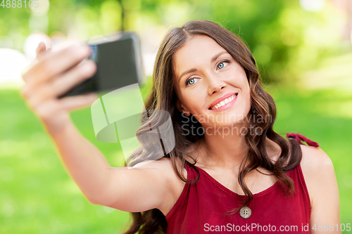 Image of happy woman with smartphone taking selfie at park