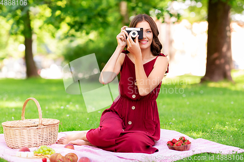 Image of happy woman with camera on picnic at park
