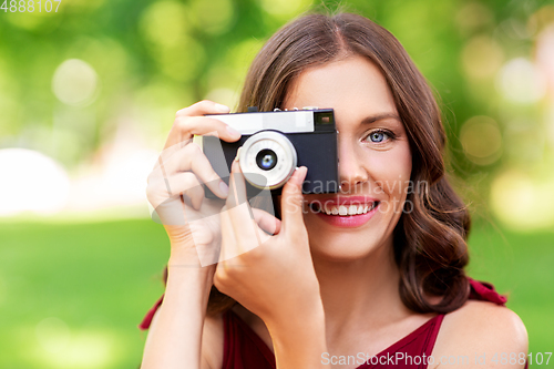 Image of happy woman with camera photographing at park